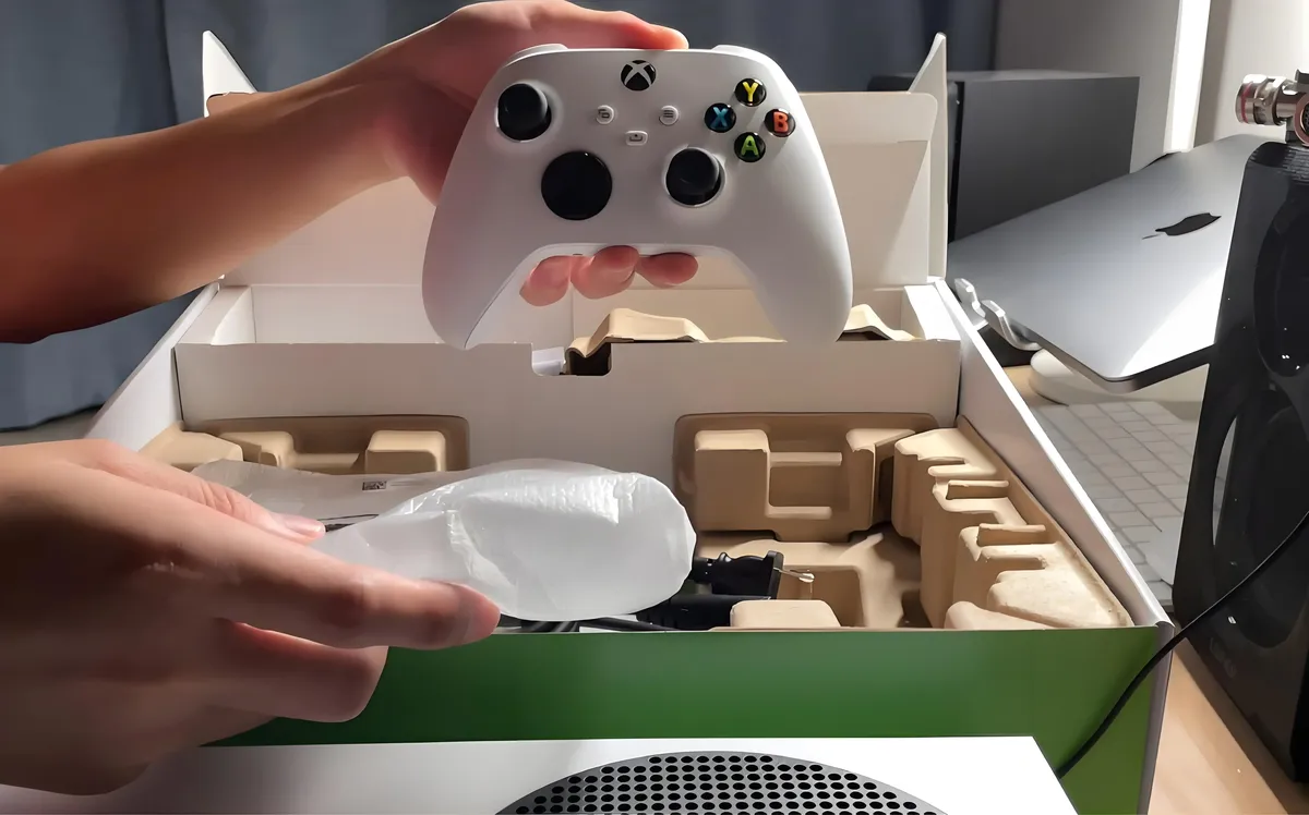 A person carefully cleaning their game console and packing it into its original box.